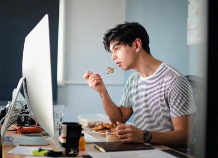 Man eating in front of his computer