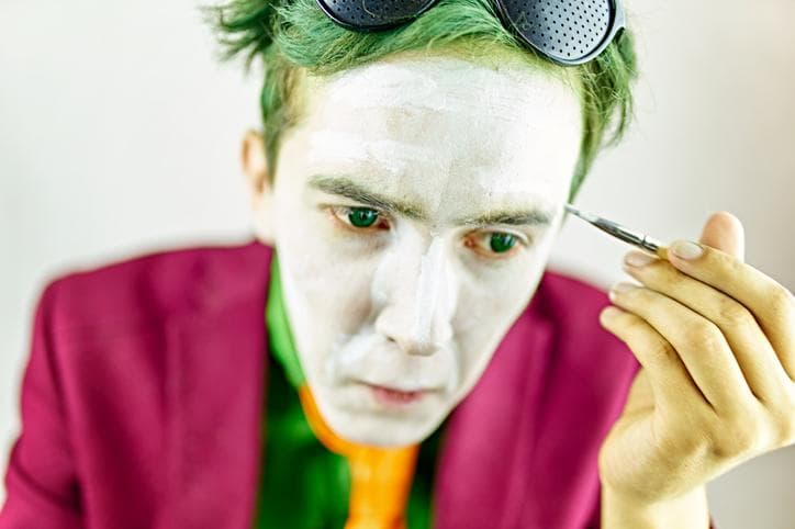 Man putting on clown make-up