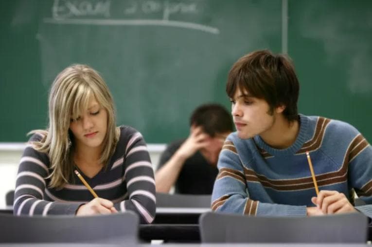 Young man copying another student's work