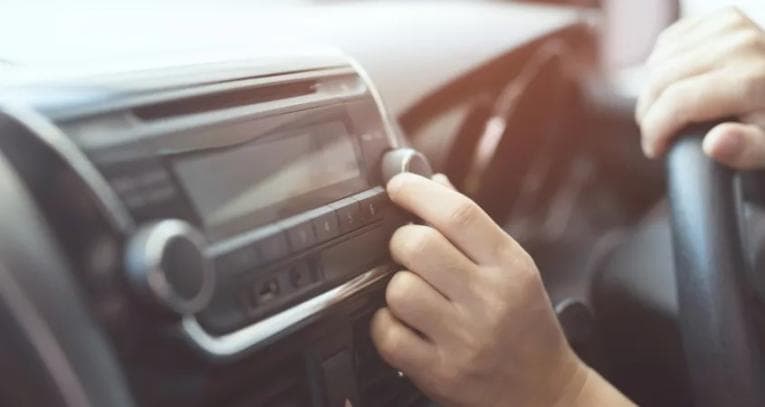 Man adjusting car radio while driving