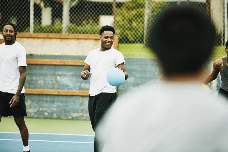 Smiling man taunting opposing team during dodgeball game