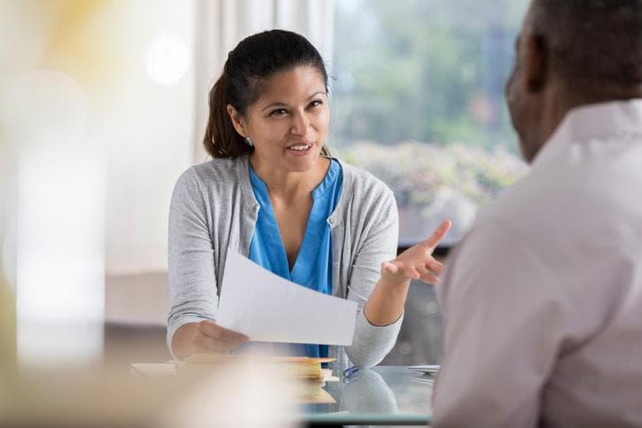 Woman holding a document and speaking to a man in an office setting