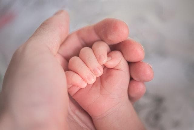 Adult holding baby's hand