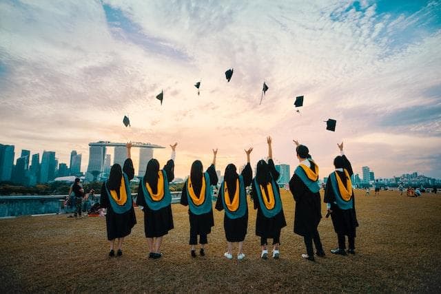 Graduates in a line throwing mortar boards in air