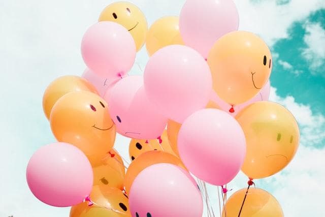 Pink and yellow balloons against a cloudy sky