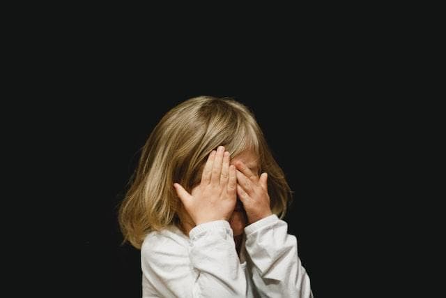 Small girl covering face with both hands