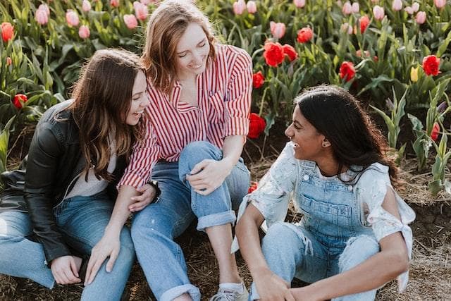 Three women talking and laughing in front of tulips