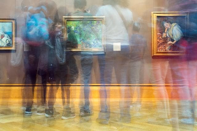 time lapse photo with blurred transparent people at an art gallery