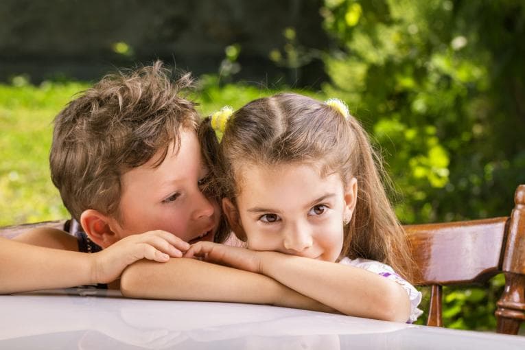 Young boy whispering to young girl