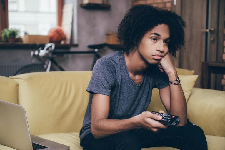 Person looking bored and pointing a remote control