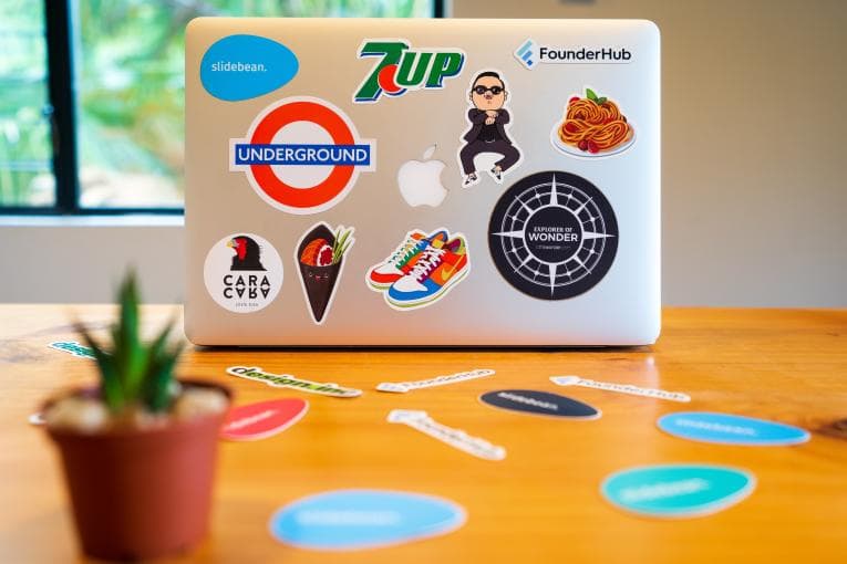 Apple laptop with different brand stickers on a desk