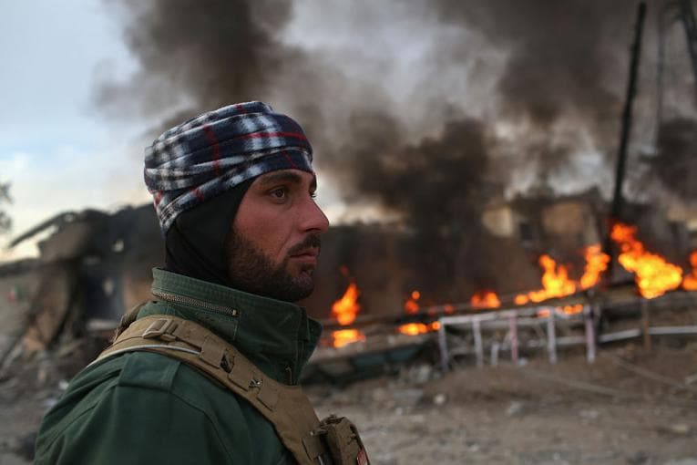 Iraqi soldier in front of burning buildings