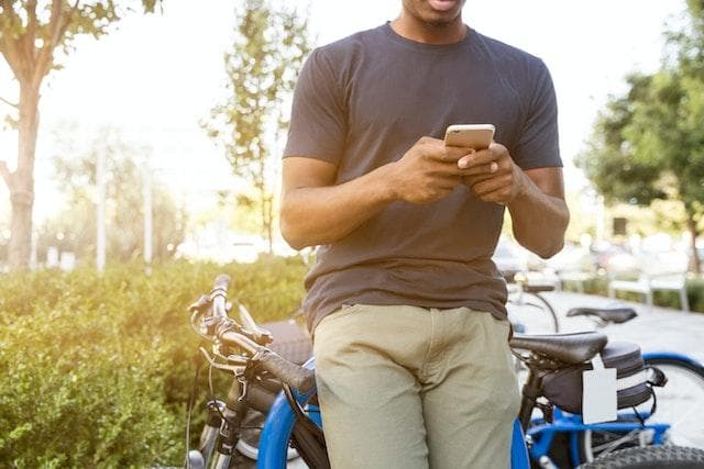 Man leaning on motorbike looking at phone