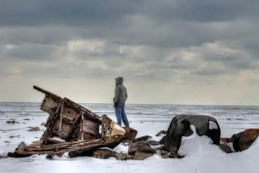 Person standing on rocks looking out to sea