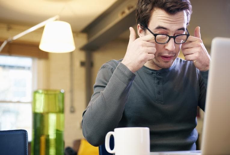 Person sitting at computer rubbing eyes