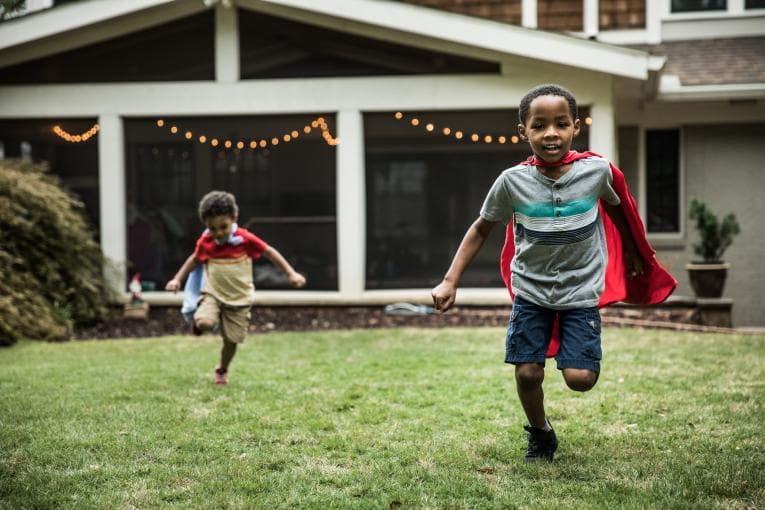 Two young boys wearing capes playing in the garden