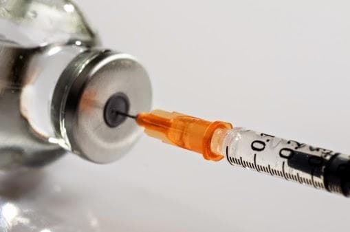 A syringe piercing a vial