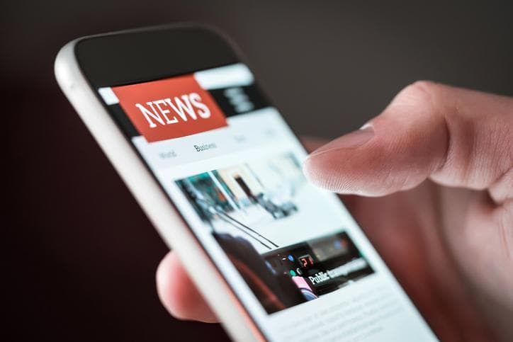 close-up of person scrolling news on their phone