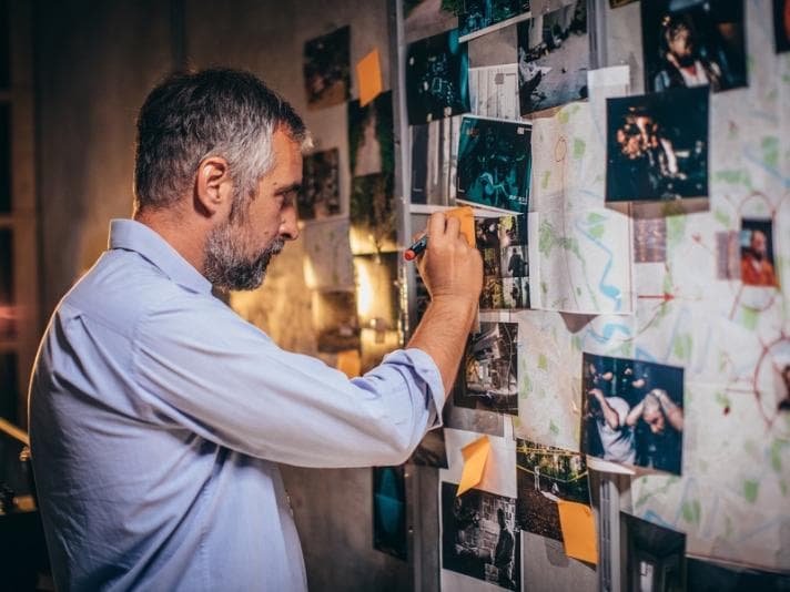 Detective examining photographs on a wall