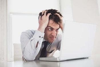 Man holding hair staring at laptop