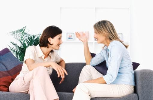 Two ladies sitting on a couch and talking