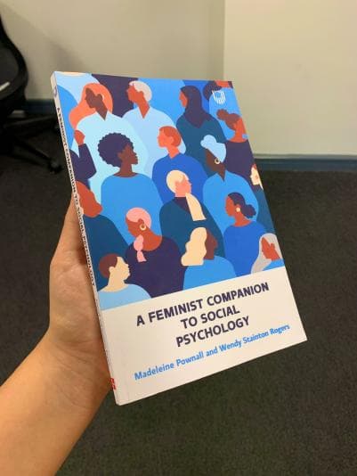 Author, Madeline Pownall holds her book showing the cover of a feminist companion to social psychology 