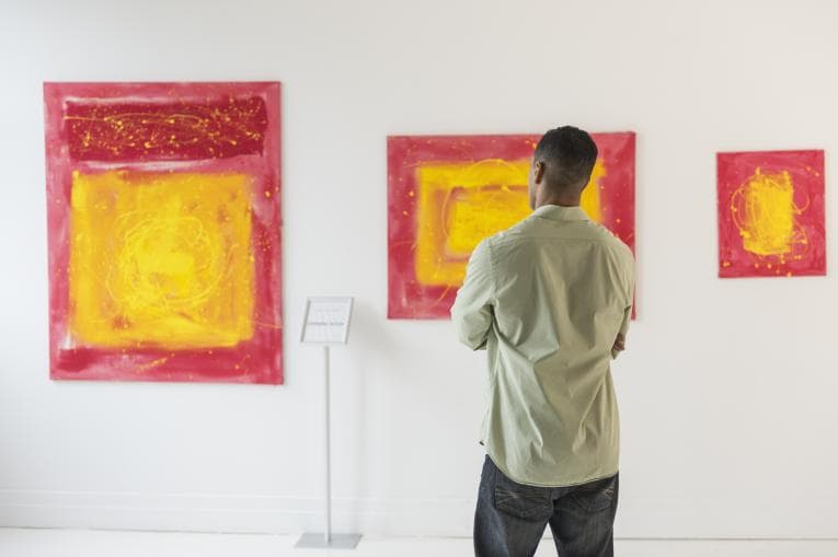 Man looking at paintings in art gallery