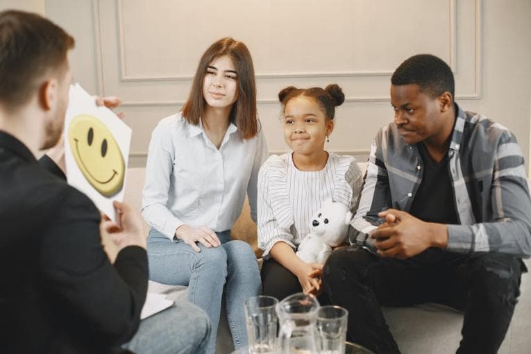 Mum, dad and daughter talking with with a therapist on a couch