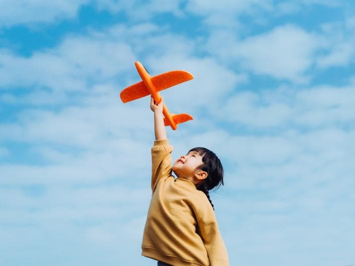 Child lifting a toy plane to the sky