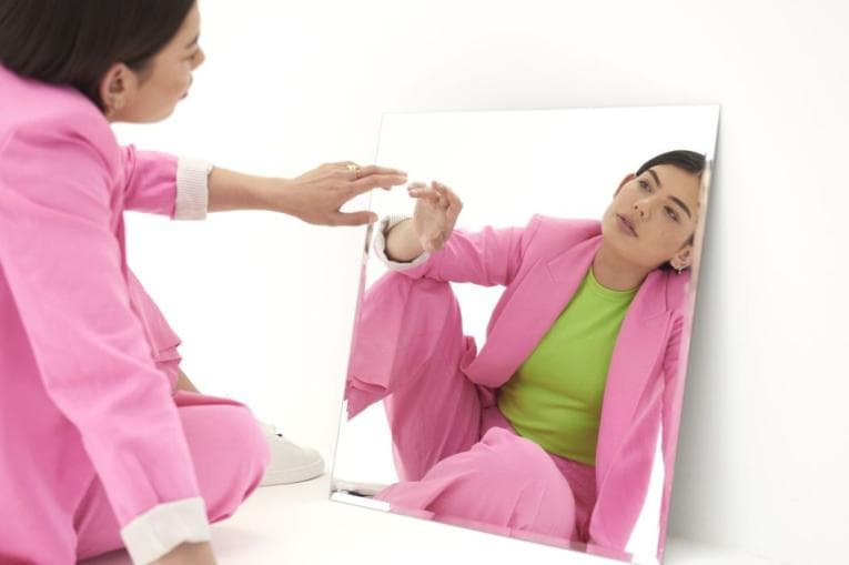 Woman with pink suit looking in mirror