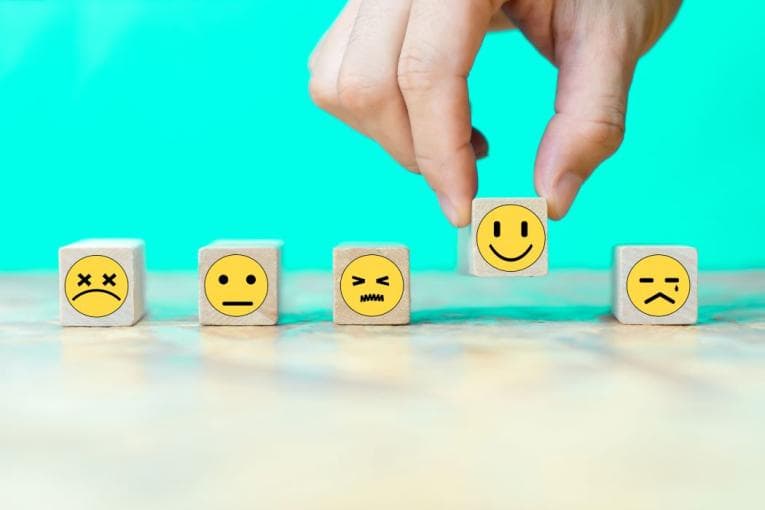 Wooden blocks with emojis depicting happy sad angry faces