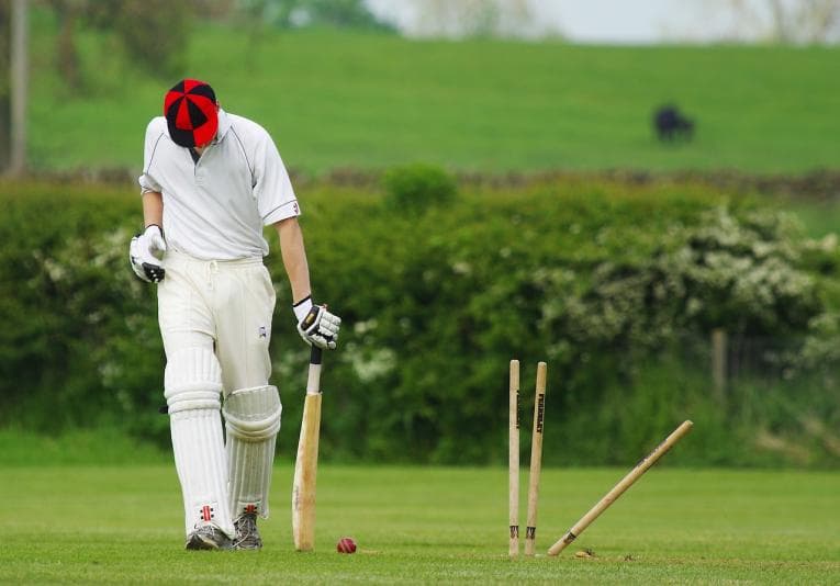 Cricket player walking off after being bowled out