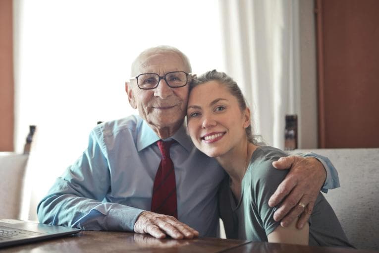 Young woman and elderly man smiling and hugging