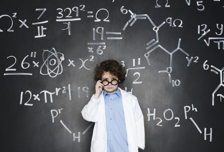 Child genius in white coat in front of formulas