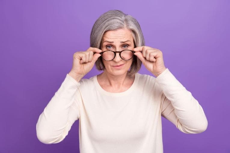 Woman looking possibly cynically over her glasses