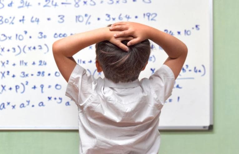 Child with hands on head in despair at a maths question