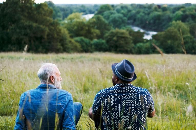 Two men sat in a field talking