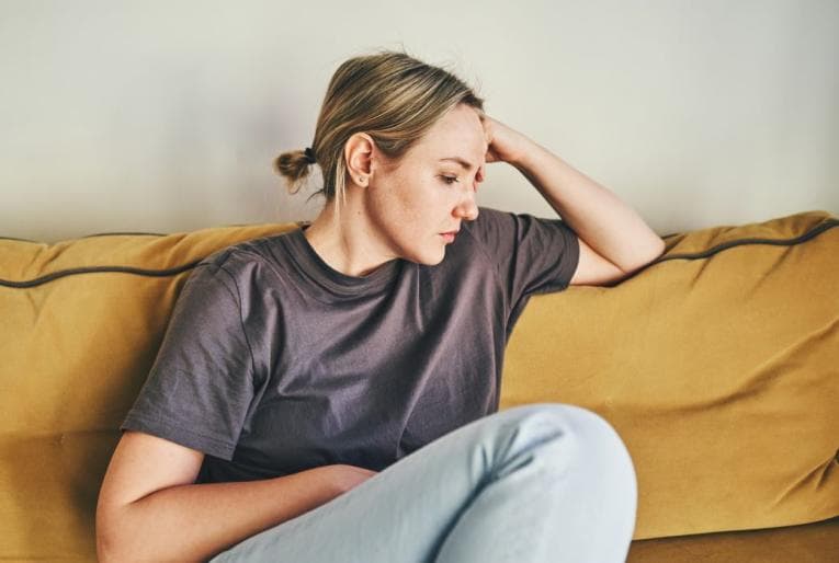 Person sitting on sofa looking sad