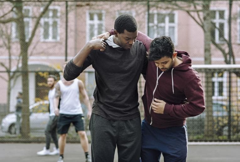 Person helping someone with an injury off the basketball court