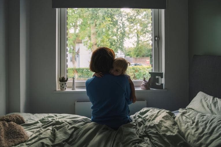 Person holding baby gazes out of the window