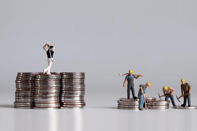 Miniature people, one golfing atop a large pile of money, and several working atop a much smaller pile of money.