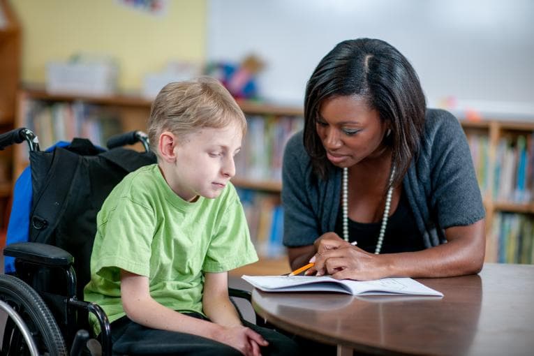 A pupil in a wheelchair with a teacher