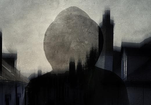 Hooded figure with buildings in background