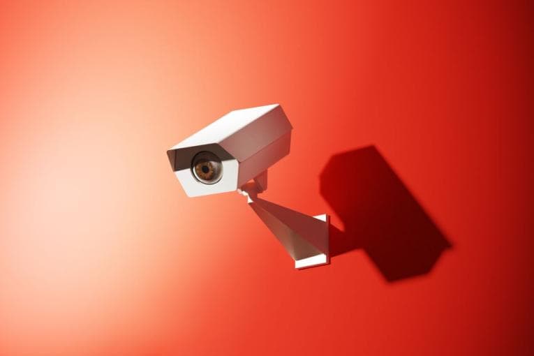 A single surveillance camera on an orange background