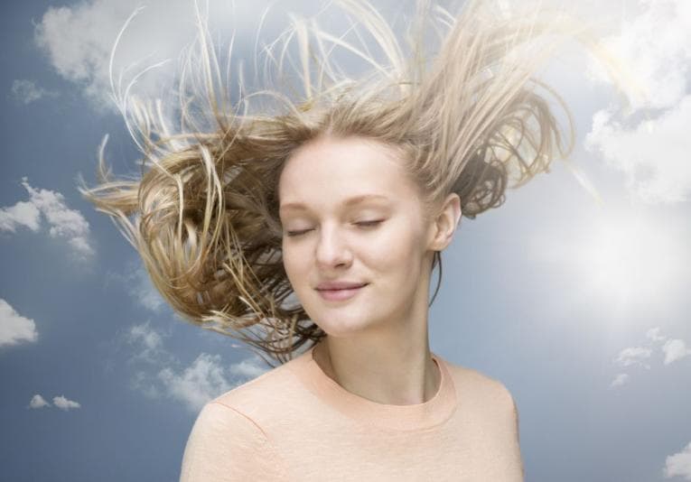 Person with flowing blonde hair in a dreamscape sky