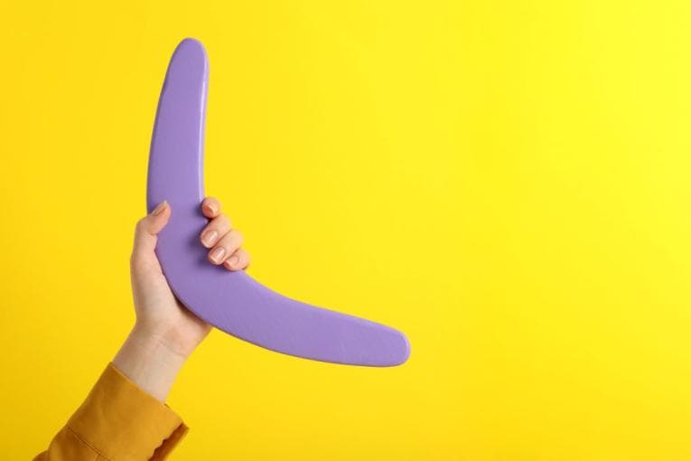 Lilac boomerang held by a hand against a yellow background